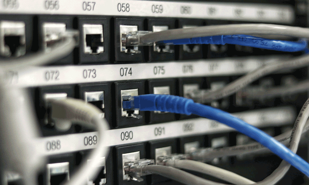 network-data-centre In einem Computer-Rechenzentrum stecken zahlreiche Kabel in nummerierte Steckdosen.